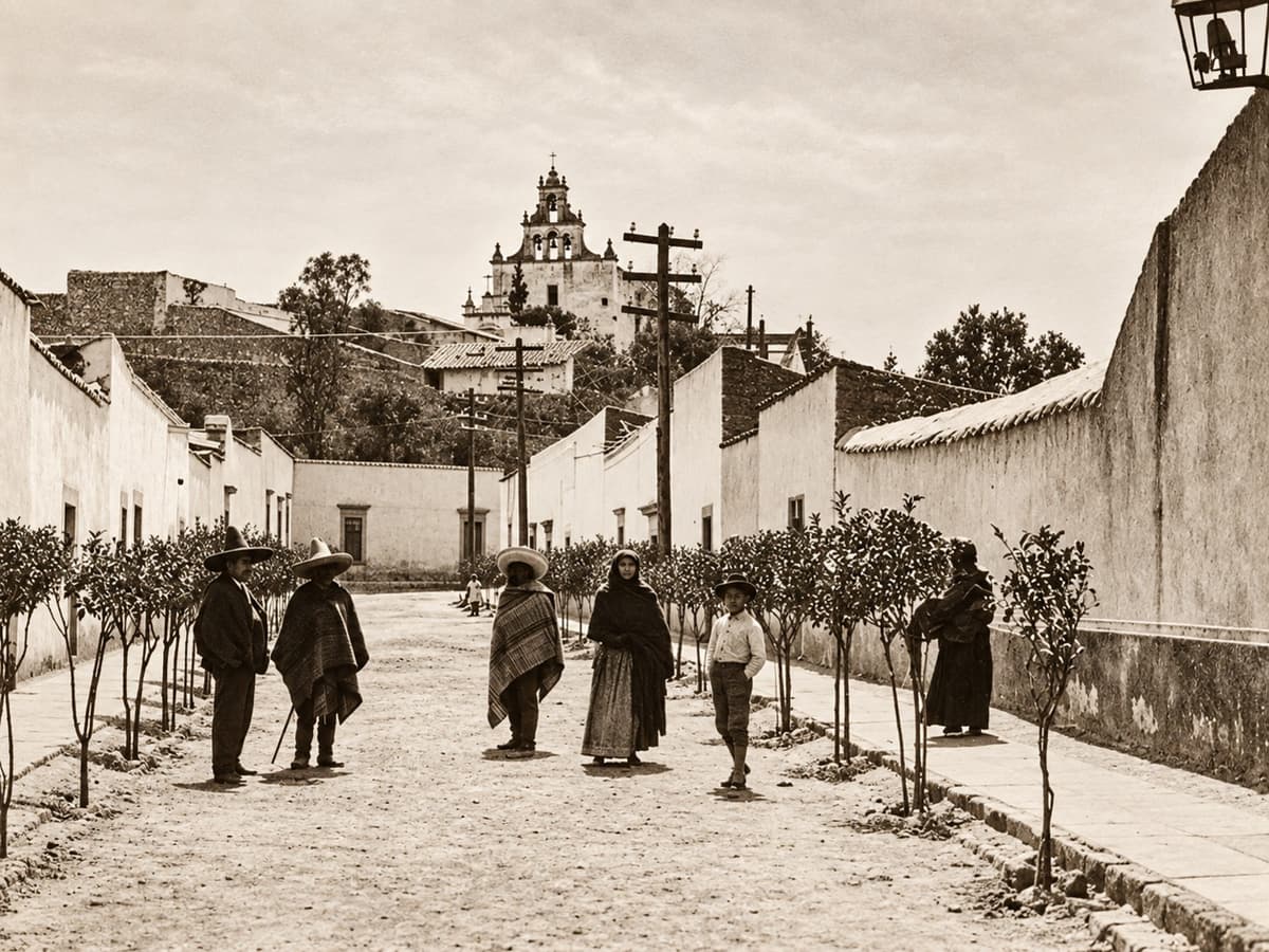 Fotografía antigua de la calle de Cóporo con árboles jóvenes, personas con sarape y un templo al fondo